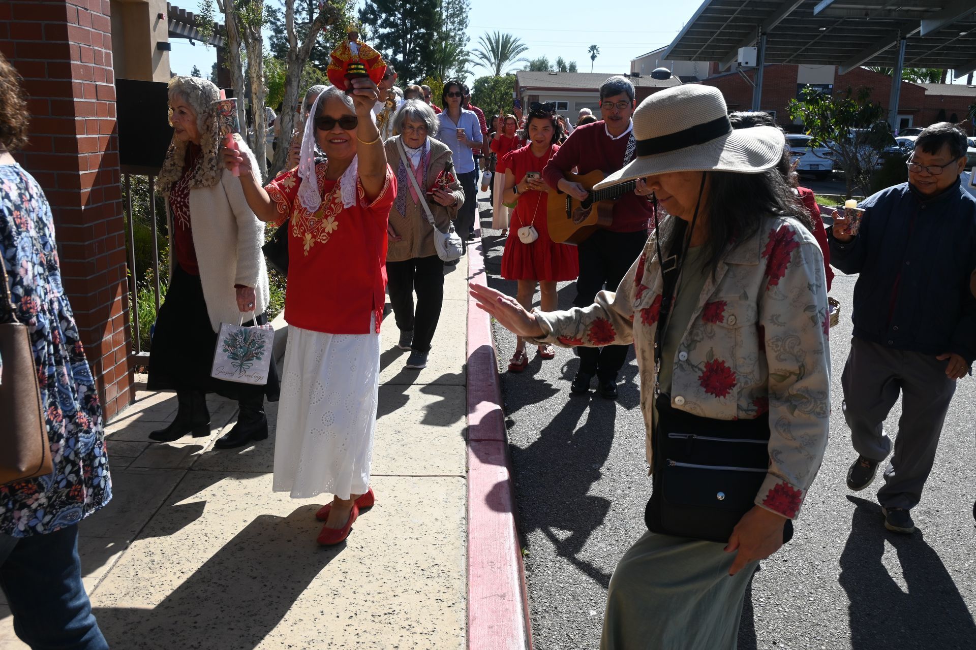 People dancing outdoors in colorful clothing, with a crowd and solar panels in the background