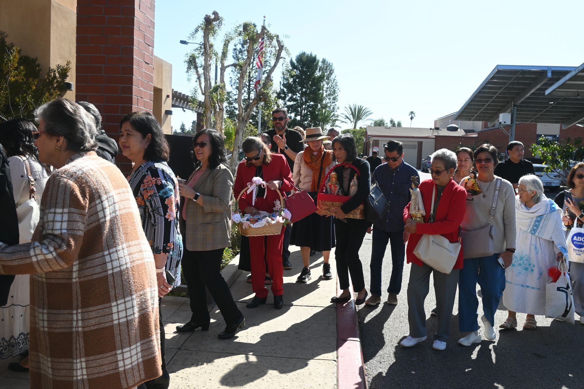 People walking in a courtyard, some holding papers, near a brick building and solar panels.