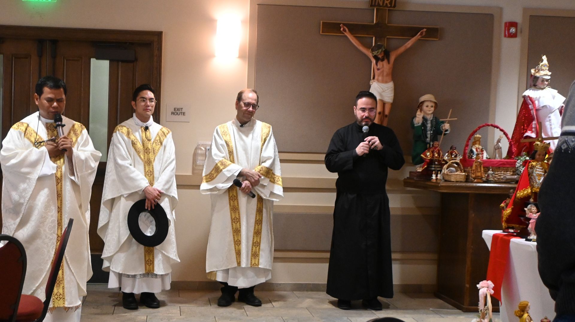 Clergy in white and black vestments stand at an altar during a church ceremony.