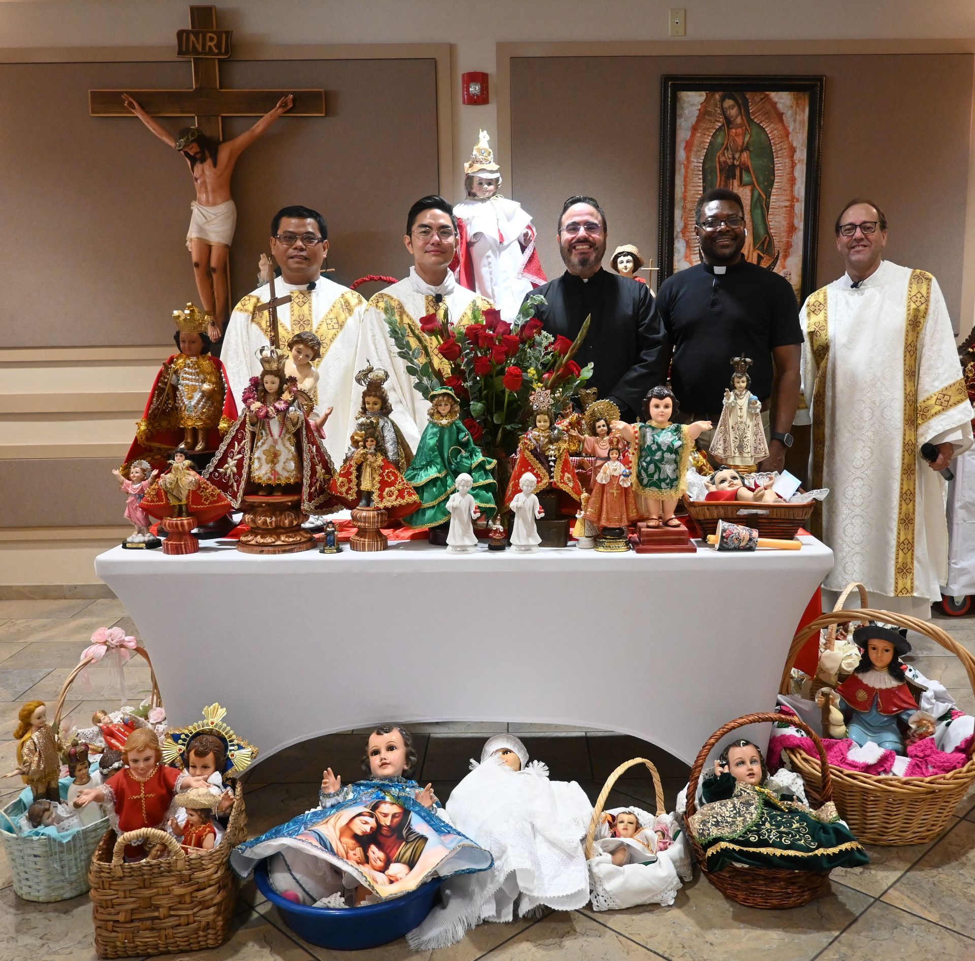 Church altar display with nativity figurines and six people standing behind it