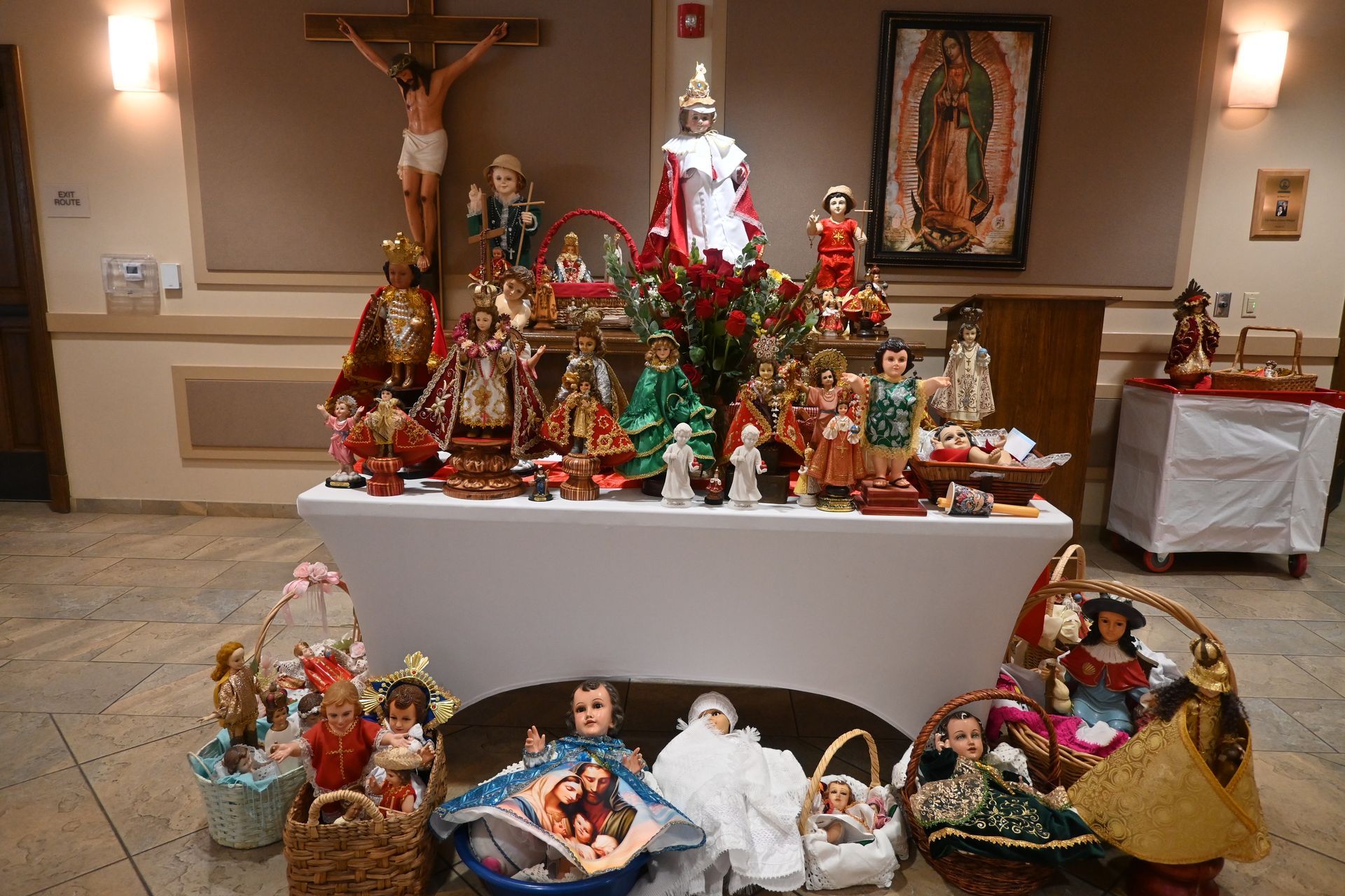 Christmas nativity display with figurines arranged on a church altar and table.
