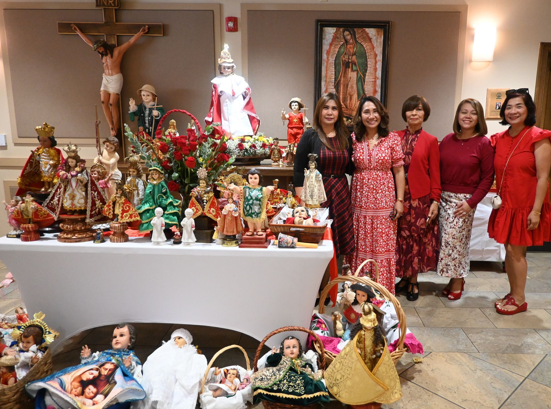 Group posing beside a festive display of religious figurines and a crucifix in a church hall