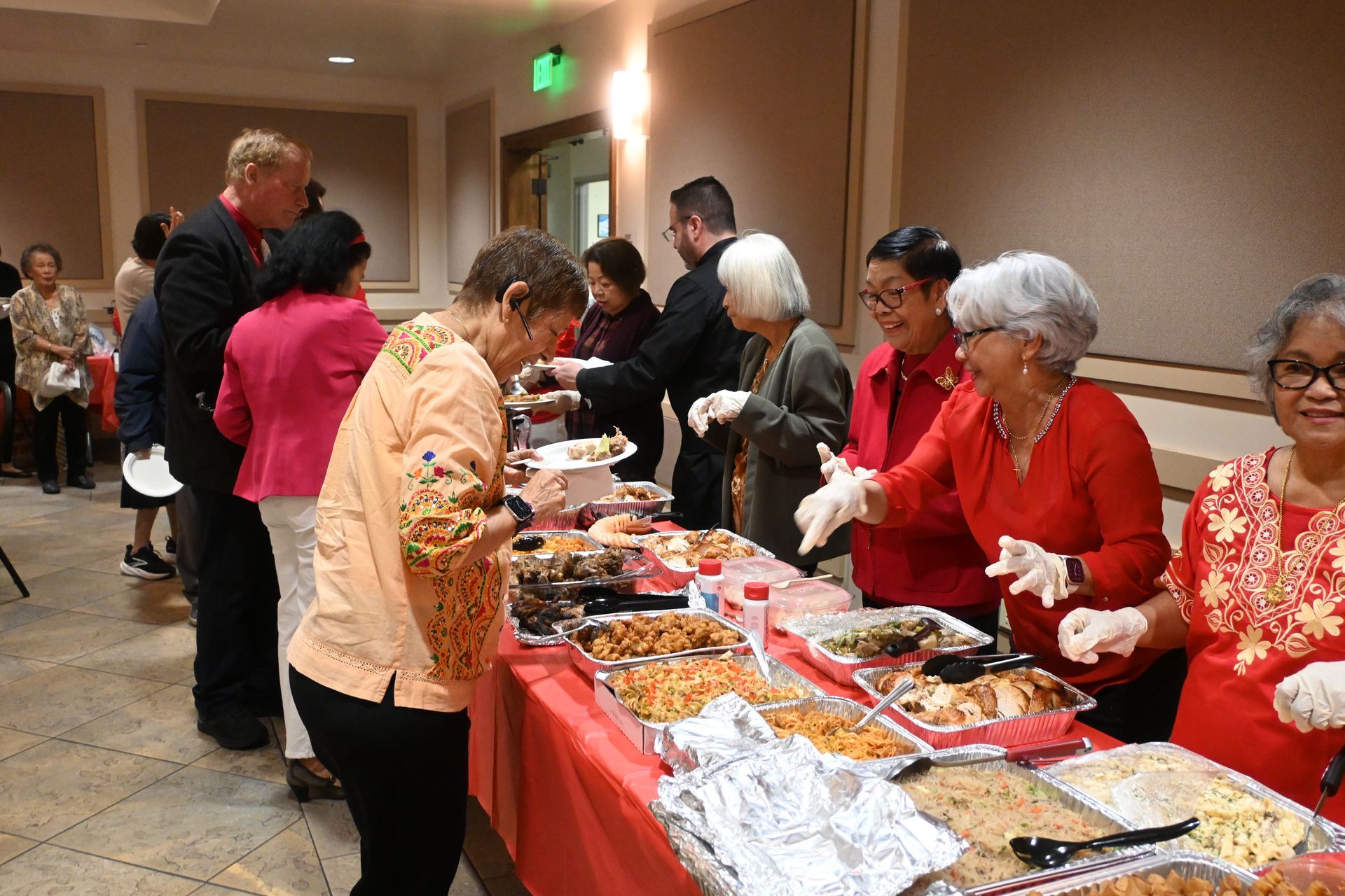 People serving food at a buffet table in a hallway banquet setting