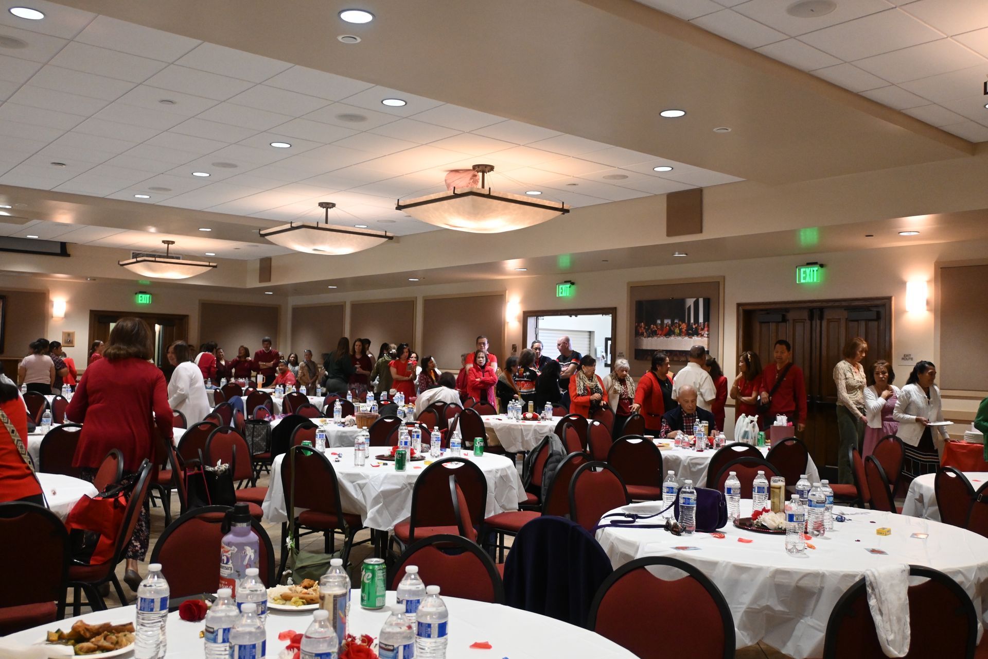 Banquet hall with round tables, red chairs, and people in red shirts gathered for a community event
