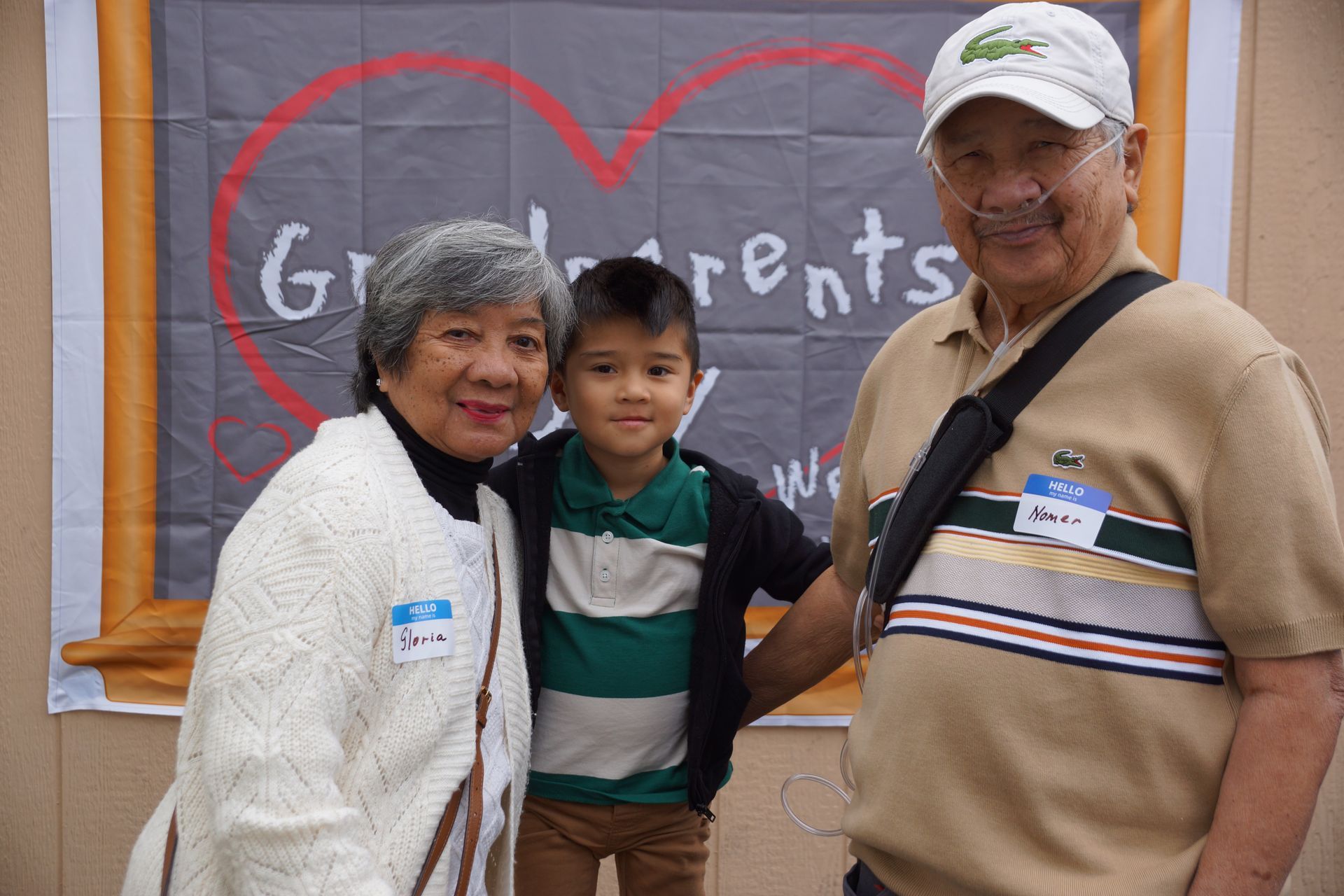 Three people smiling in front of a chalkboard with a red heart and the word “Parents.”