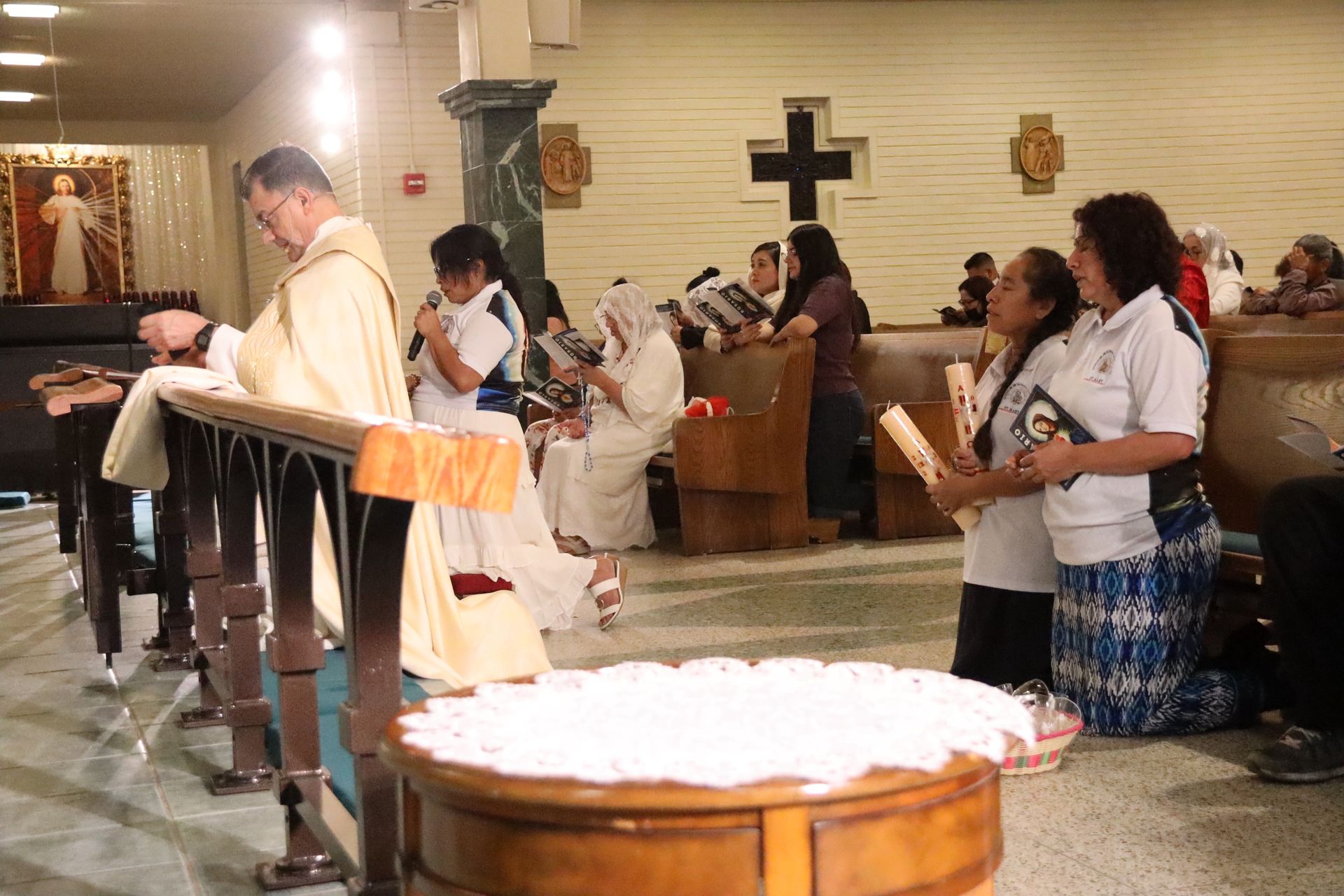 Priest and congregation standing in church during a service, with a baptismal font in the foreground