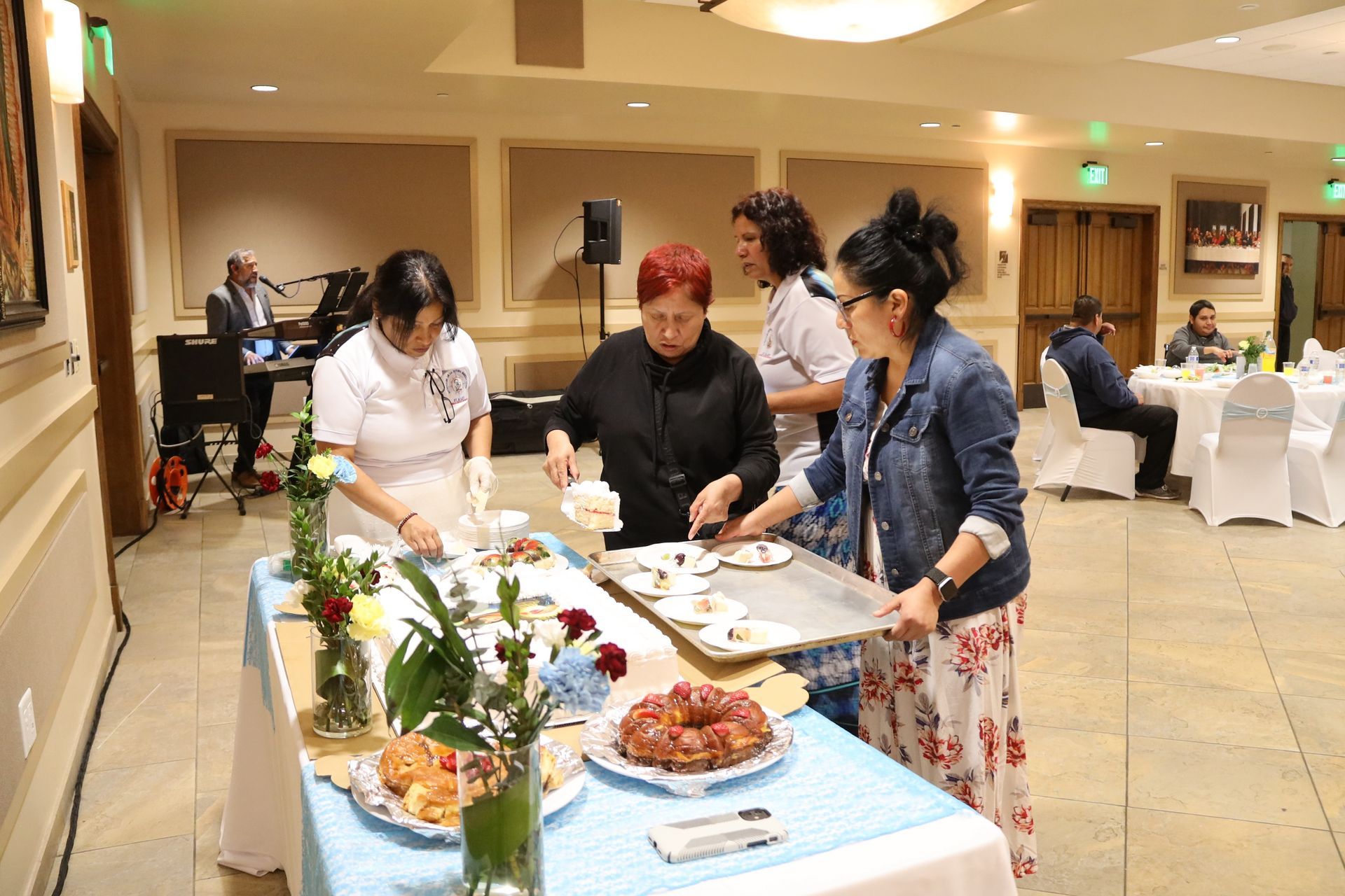 People serving food at a buffet table in a banquet hall