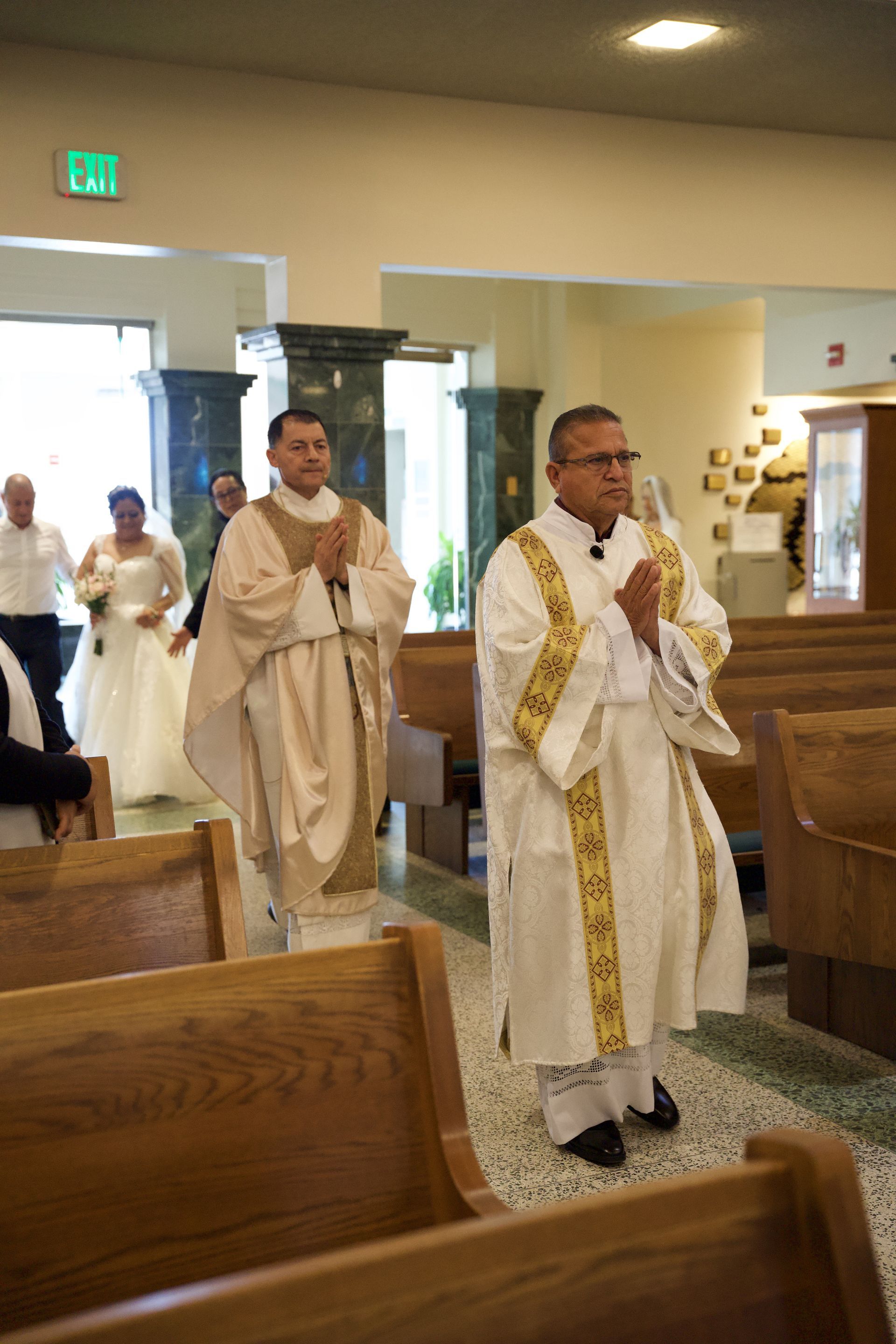 Priests in white and gold robes processing down a church aisle during a service