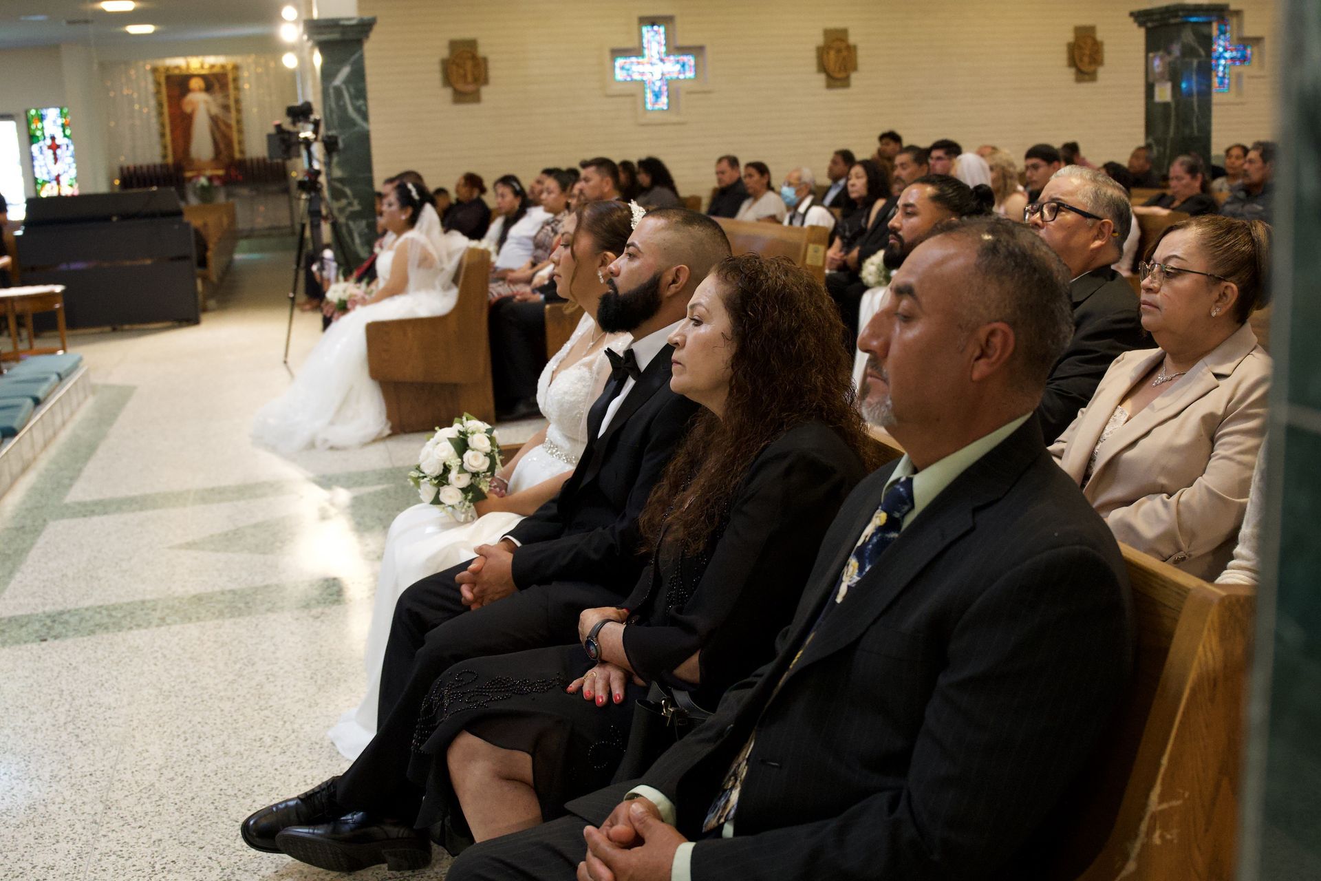 Wedding guests seated in a church, watching the ceremony near the altar