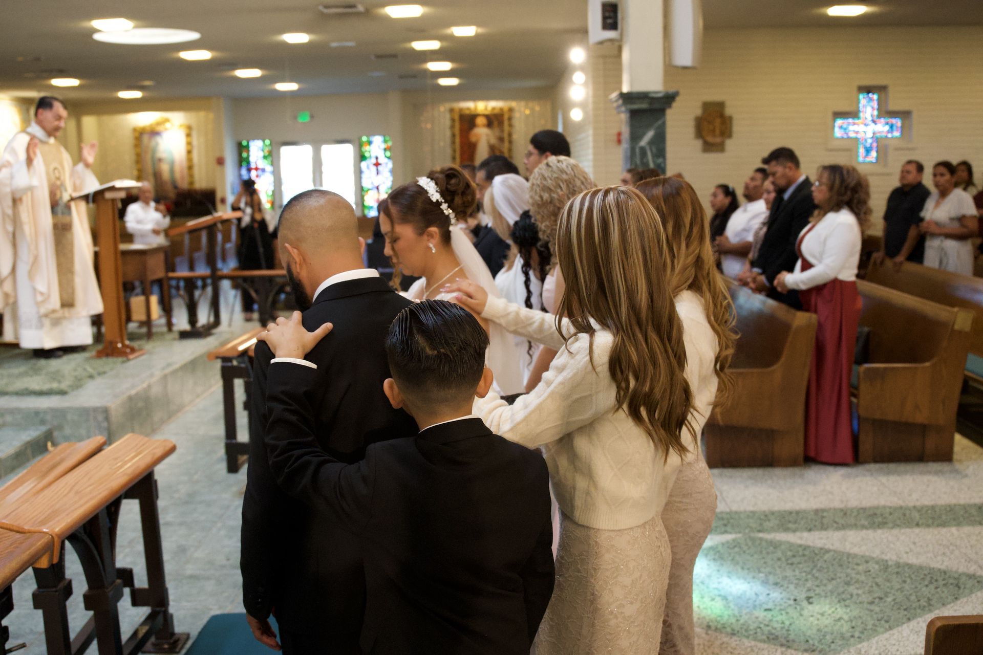 Wedding guests standing in church pews during a ceremony, facing the altar