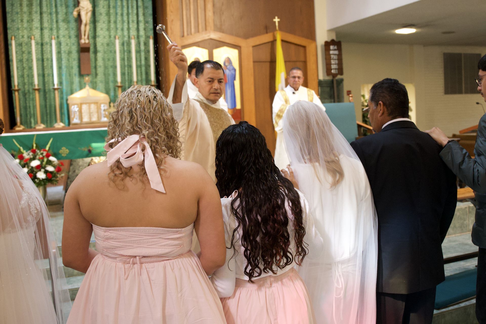 Wedding ceremony in a church, with the couple and bridal party facing the officiant at the altar.