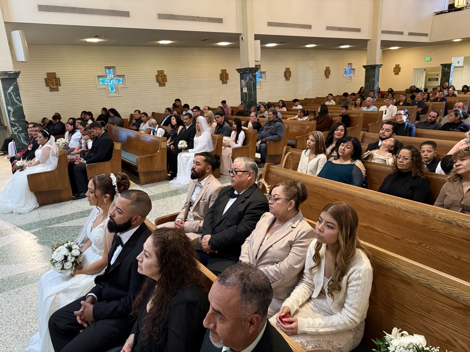Guests seated in a church pew during a wedding ceremony, with a bride and groom at the front.
