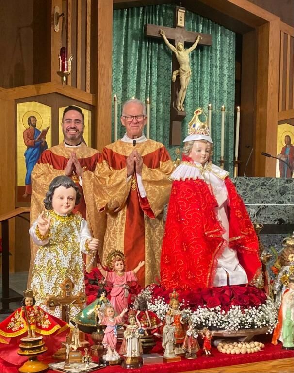 Nativity display with a crucifix and two priests behind ornate statues in a church sanctuary