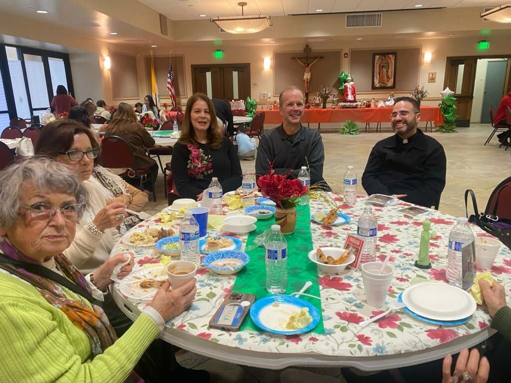 People seated at a banquet table with plates, drinks, and holiday decorations in a dining hall.
