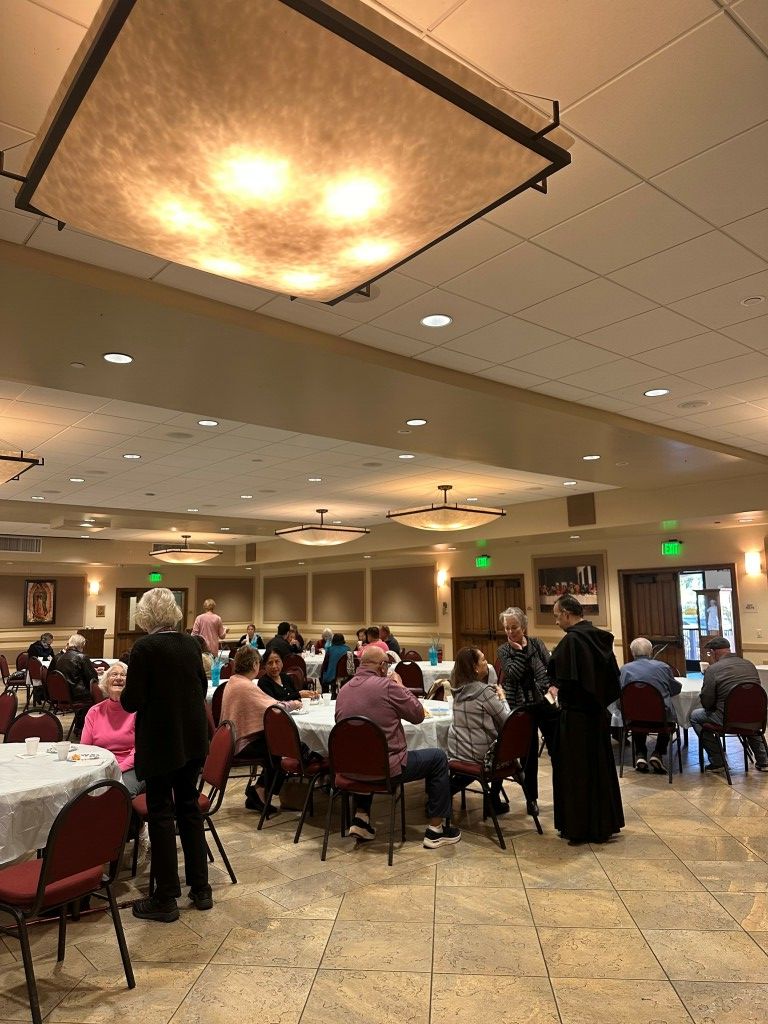 Banquet hall with people seated at round tables under warm ceiling lights