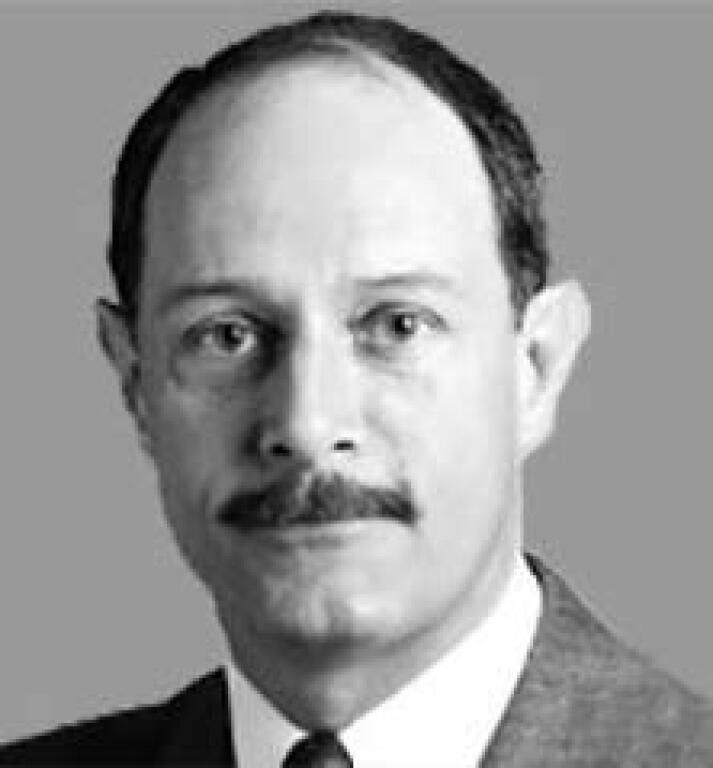 Black-and-white portrait of a man with a mustache in a suit and tie, looking at the camera.
