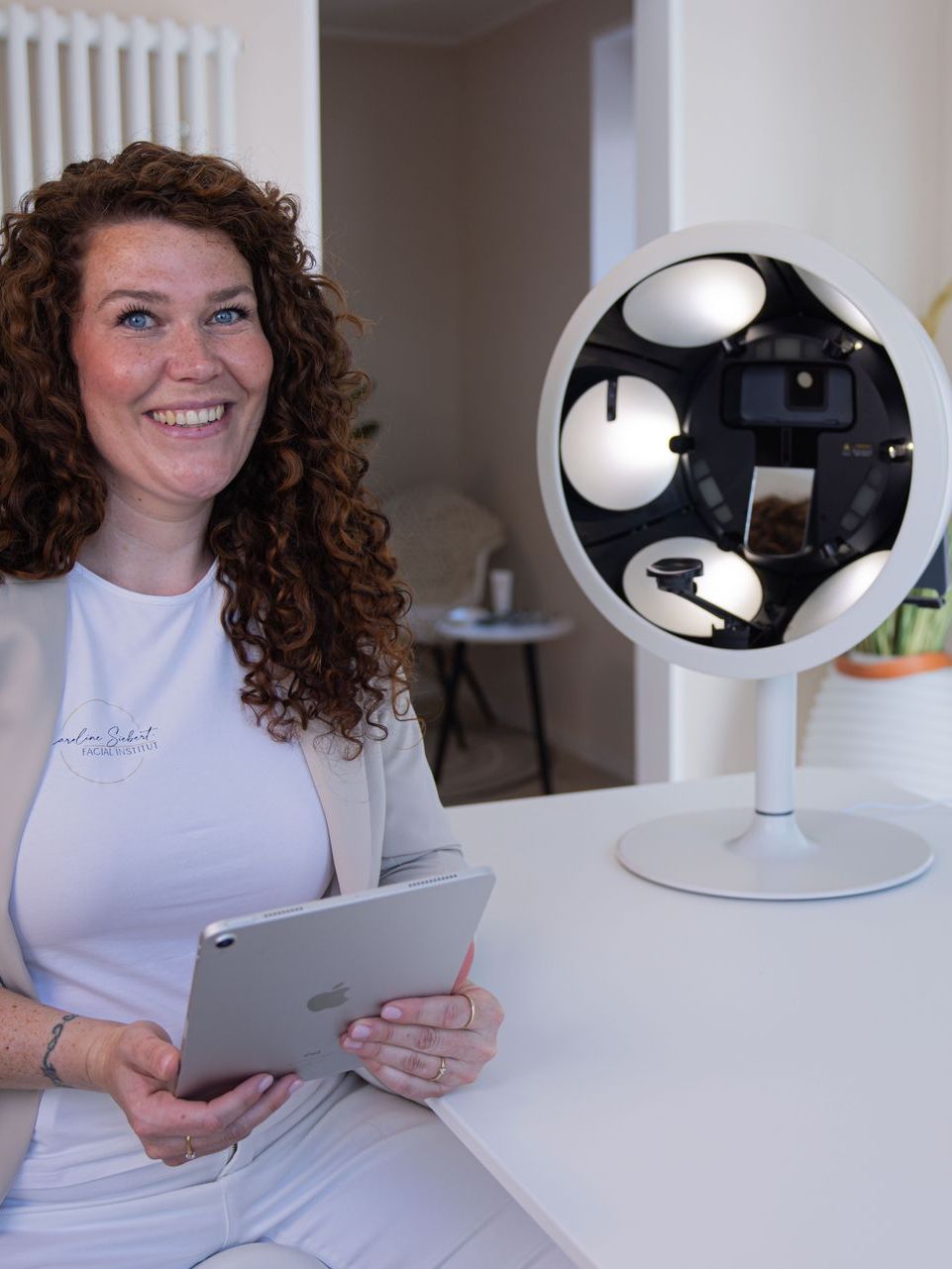 Eine Frau sitzt an einem Tisch und hält ein ipad in der Hand