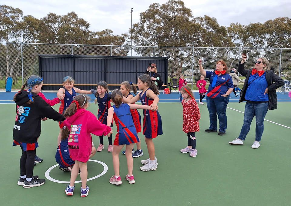 Children in red and blue uniforms playing on an outdoor sports court