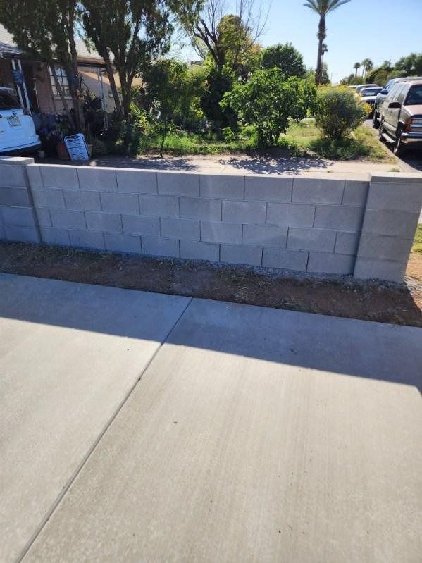 A concrete driveway with a brick wall in the background