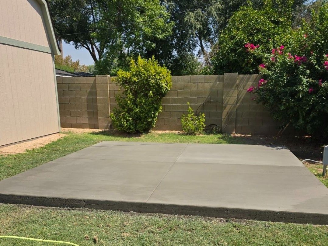 A concrete patio in the backyard of a house.