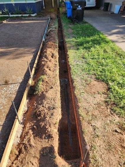 A trench is being dug in the side of a driveway.