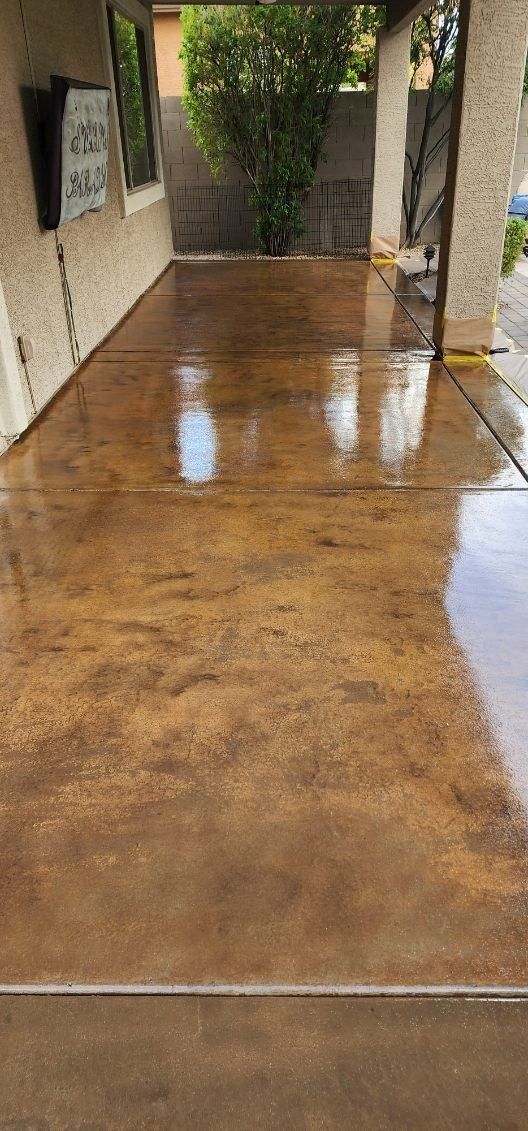 A concrete driveway leading to a house with a tree in the background.