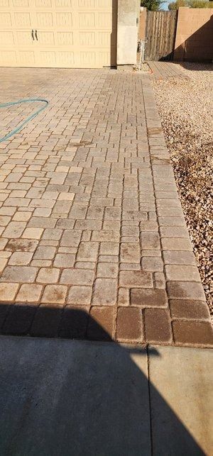 A brick walkway leading to a garage and a house.
