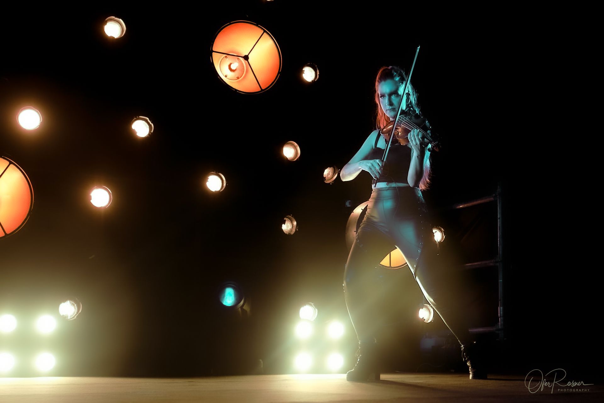 A woman is playing a violin in a dark room.
