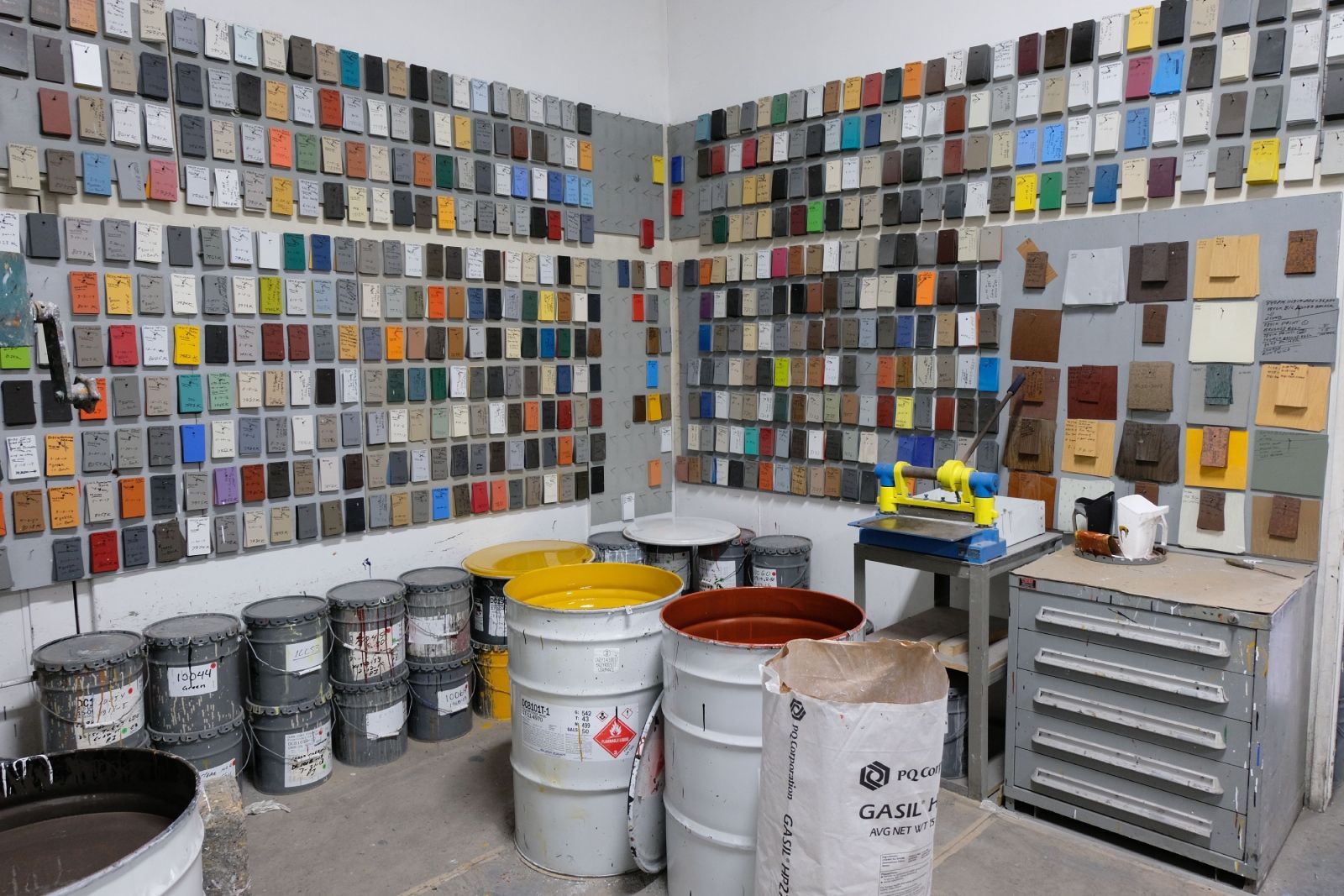 A room filled with colorful paint swatches on the walls and several paint cans.