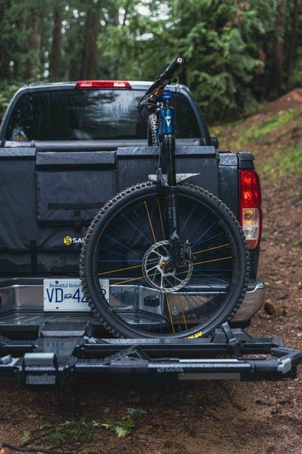 Mountain bike secured in a hitch-mounted bike rack on a pickup truck.