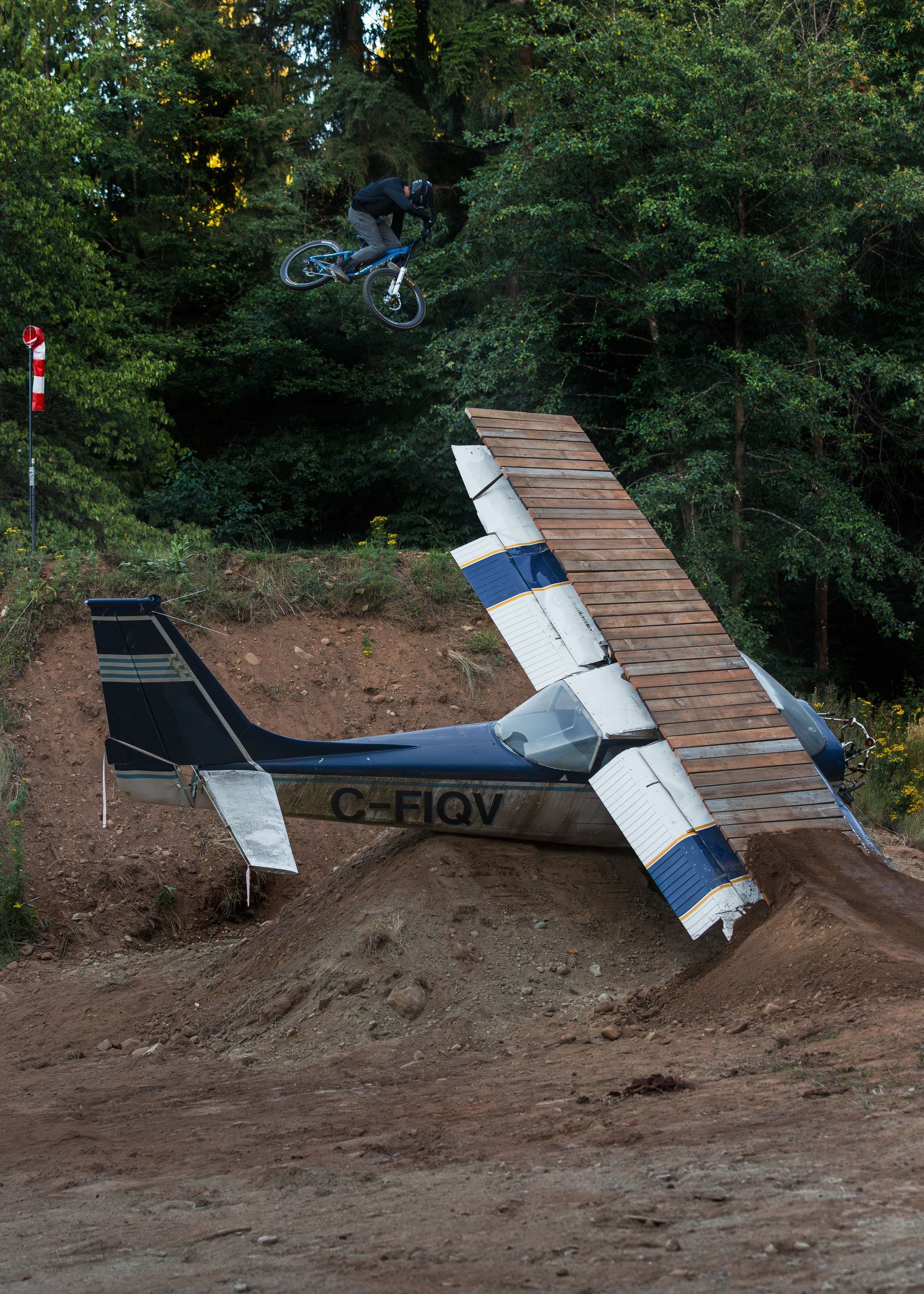 Small airplane crashed into a dirt hill, with a wooden ramp extending from the wing.