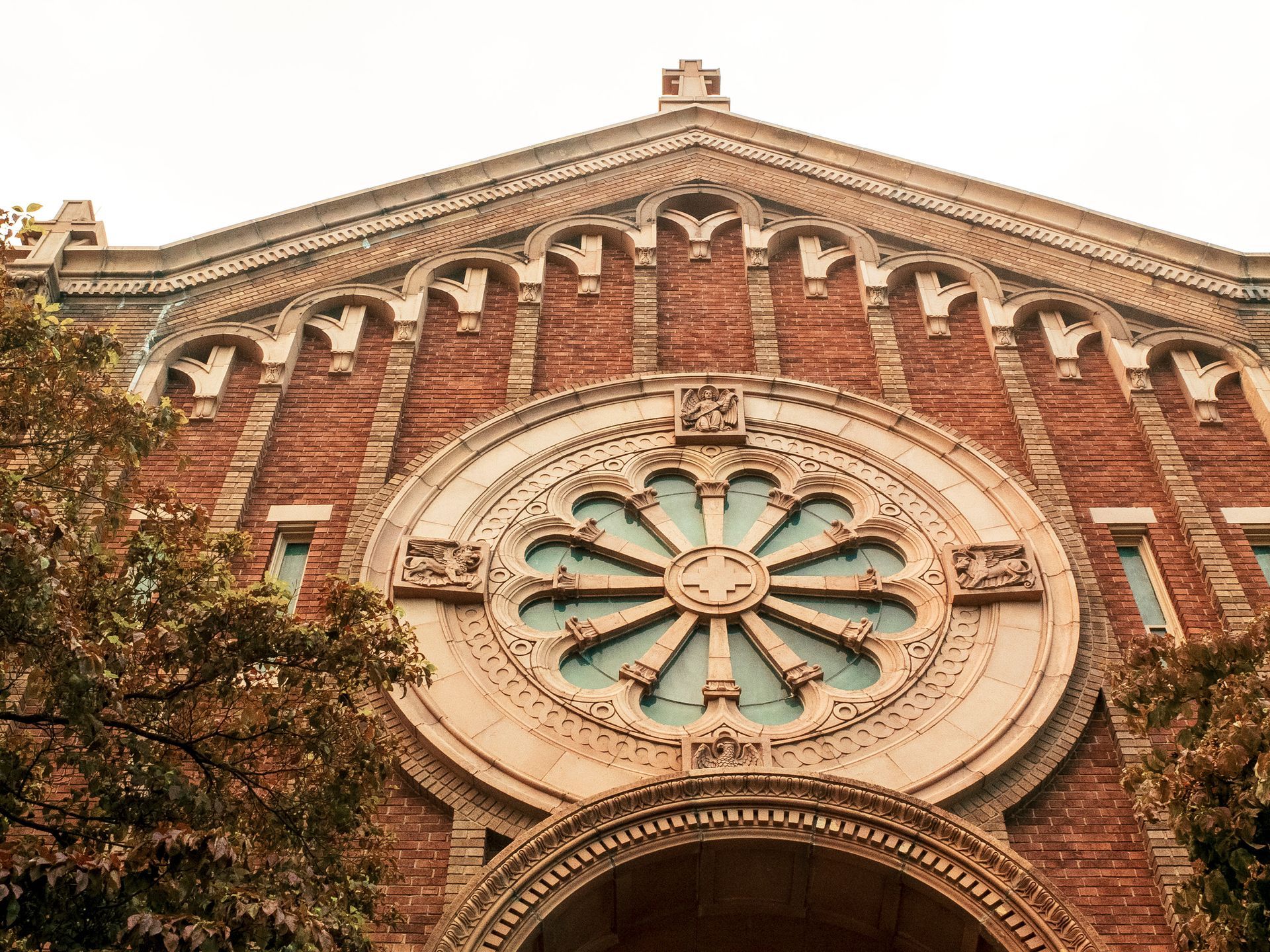 Brick church exterior with rose window and decorative archways.