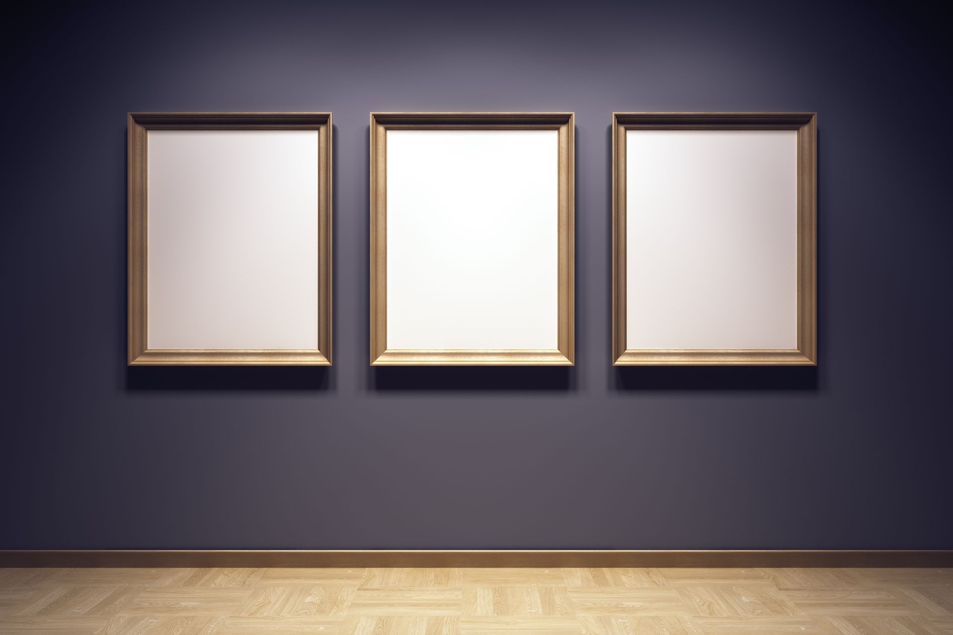 Three gold-framed blank canvases on a dark blue wall, above a light wood floor.