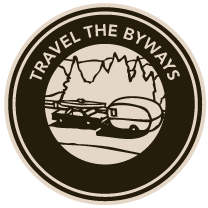 A logo for travel the byways with a trailer and mountains in the background.