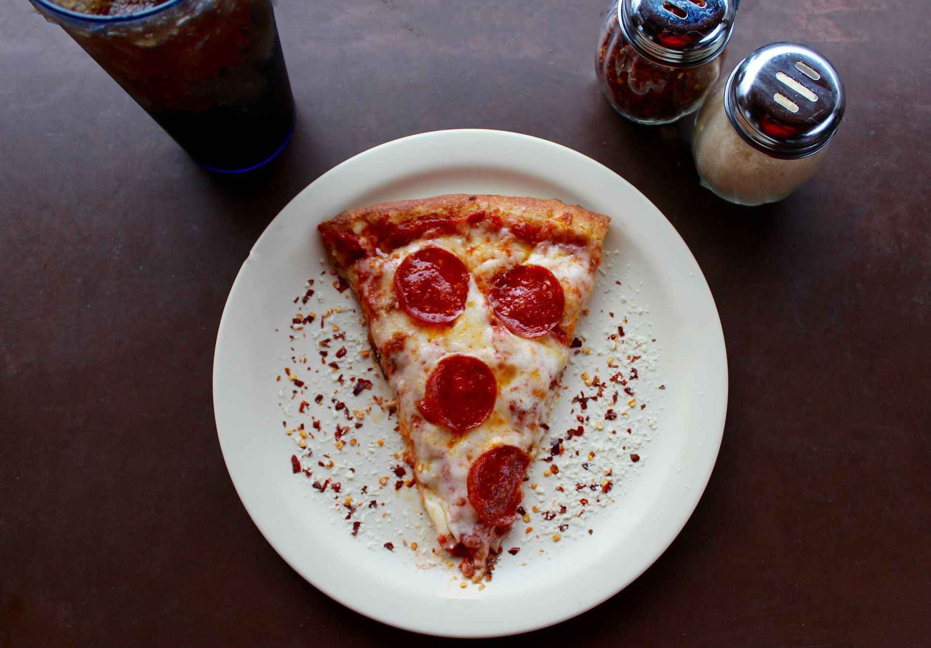 A slice of pepperoni pizza on a white plate