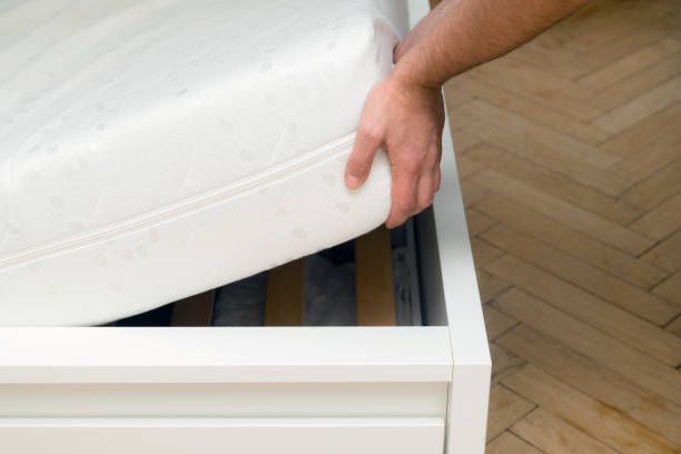 A mattress being lifted up from the corner by a man - Macomb, MI - Night Owl Express Carpet Cleaning