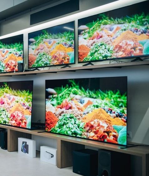 A row of televisions are lined up on a shelf in a store.