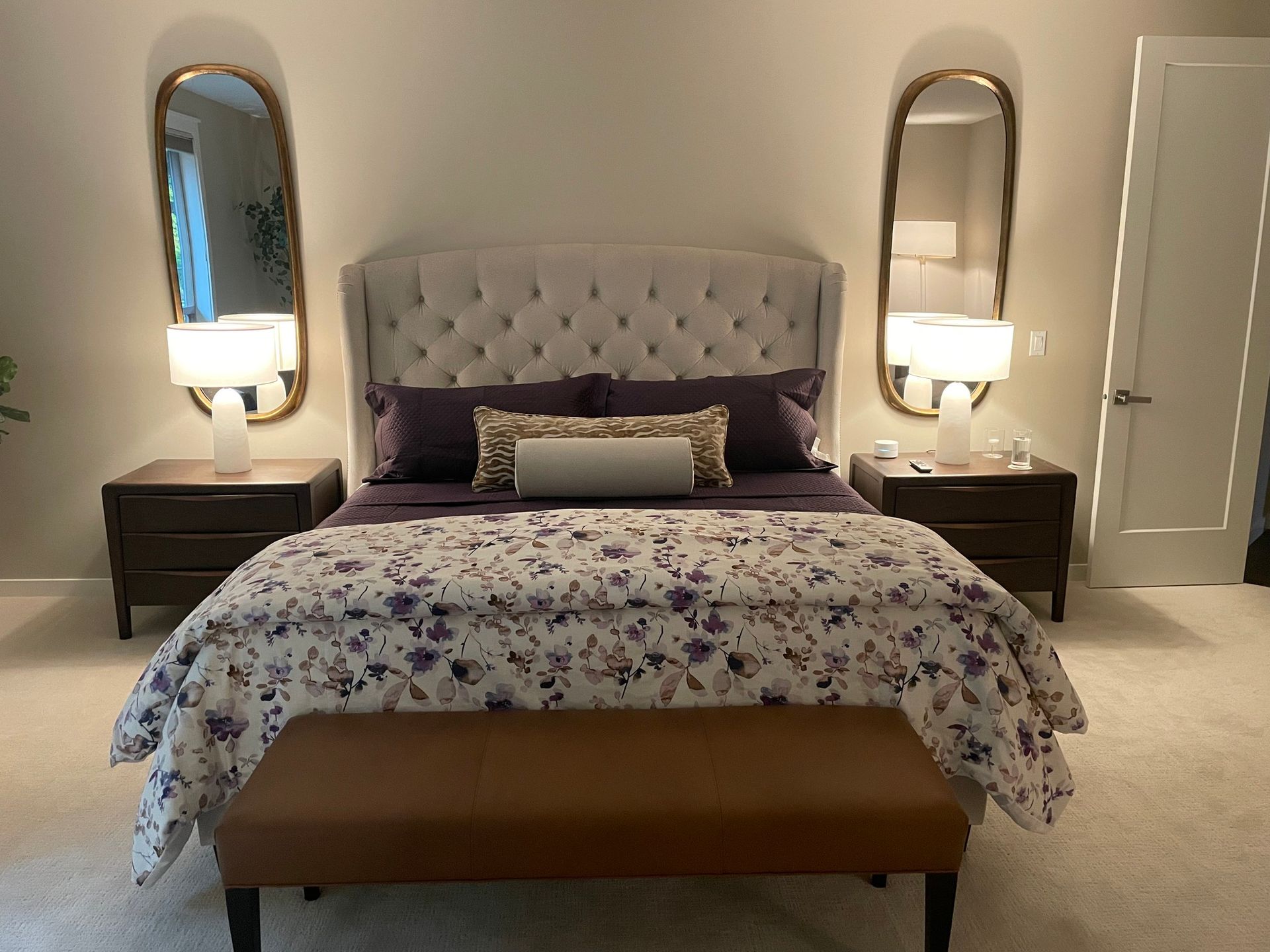 Custom bedding in a South Sound bedroom with a tufted headboard, floral duvet, and layered pillows, styled with warm lighting and matching nightstands.