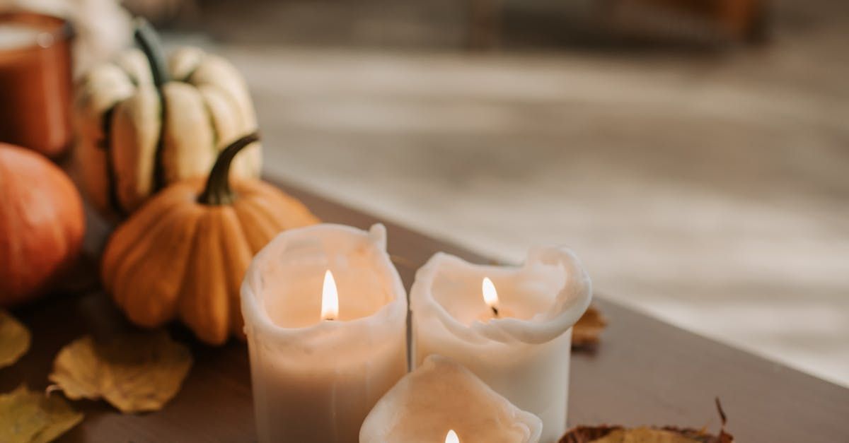 Cozy fall home decor with glowing candles, pumpkins, and autumn leaves on a rustic table.