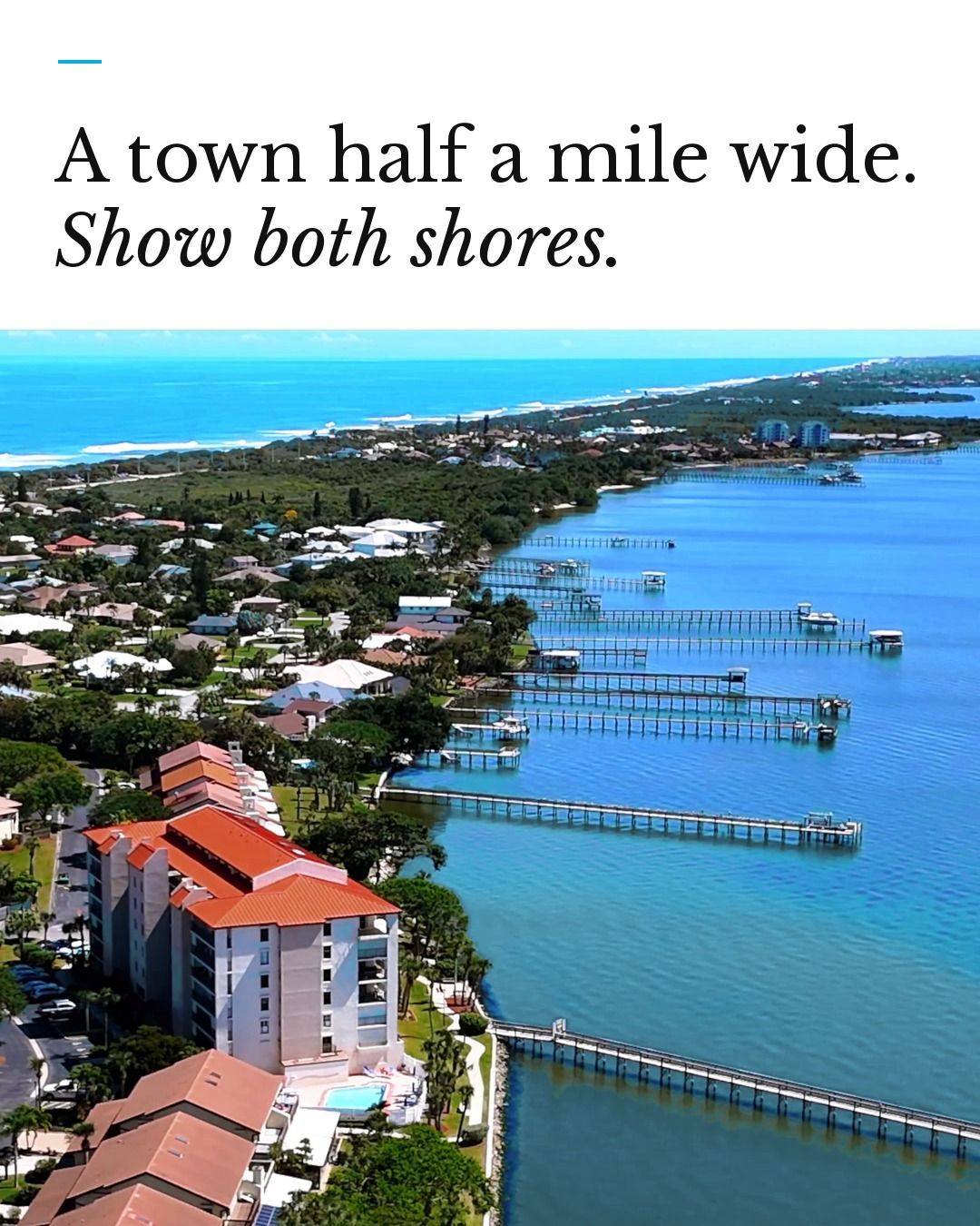 Aerial view of a coastal town half a mile wide with long piers extending into blue water.