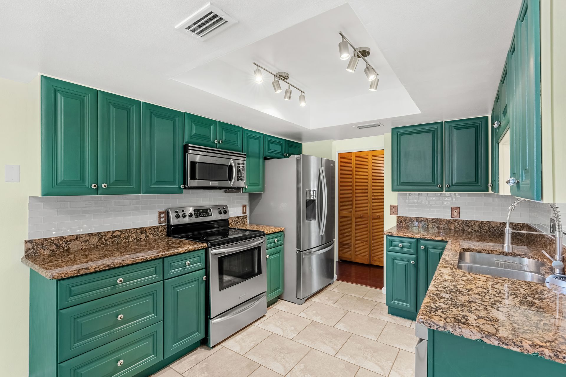 Green kitchen cabinets with stainless steel appliances and granite countertops. No HOA home in Rockledge Florida for sale