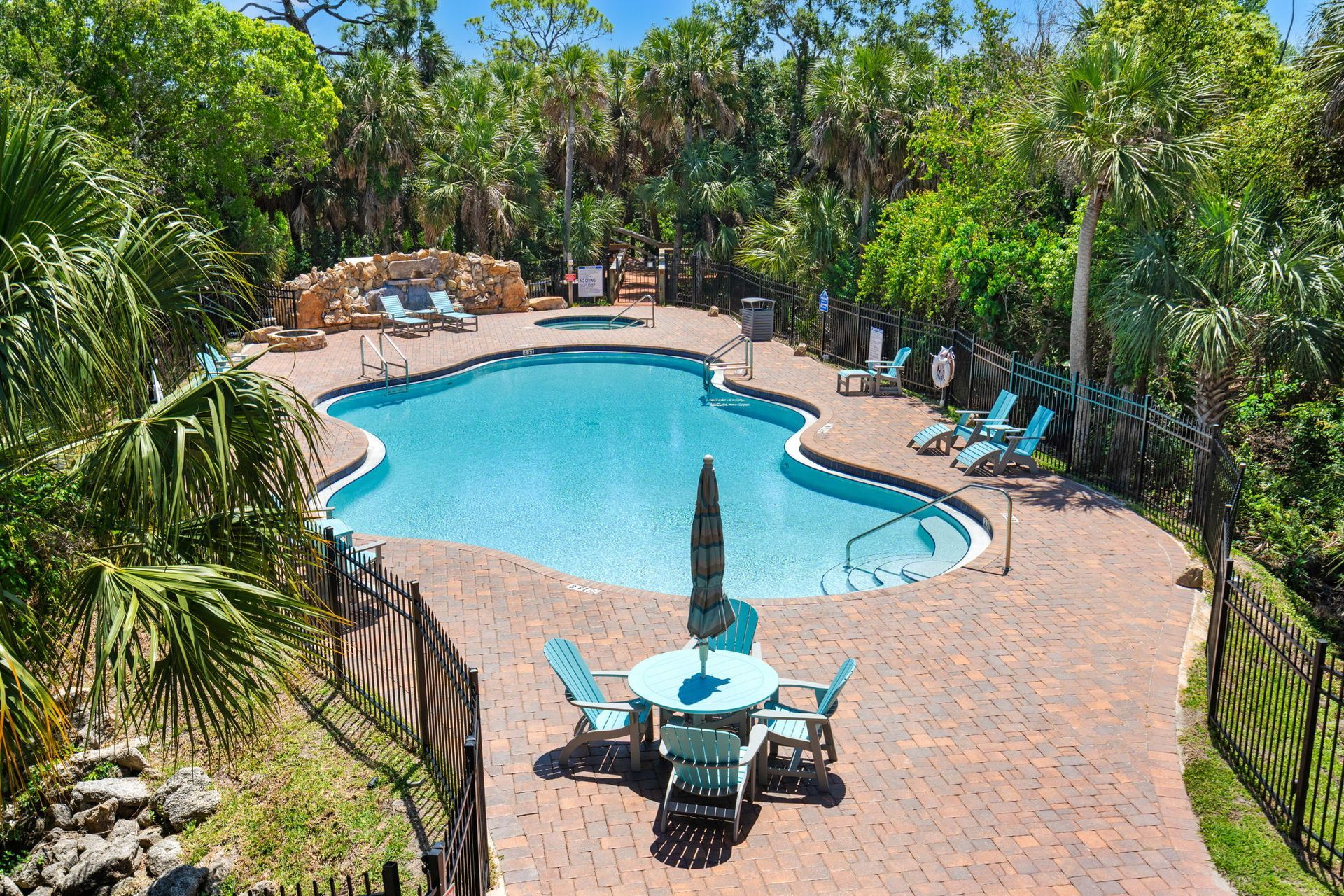 Resort pool with turquoise water, brick patio, lounge chairs, and palm trees surrounding it