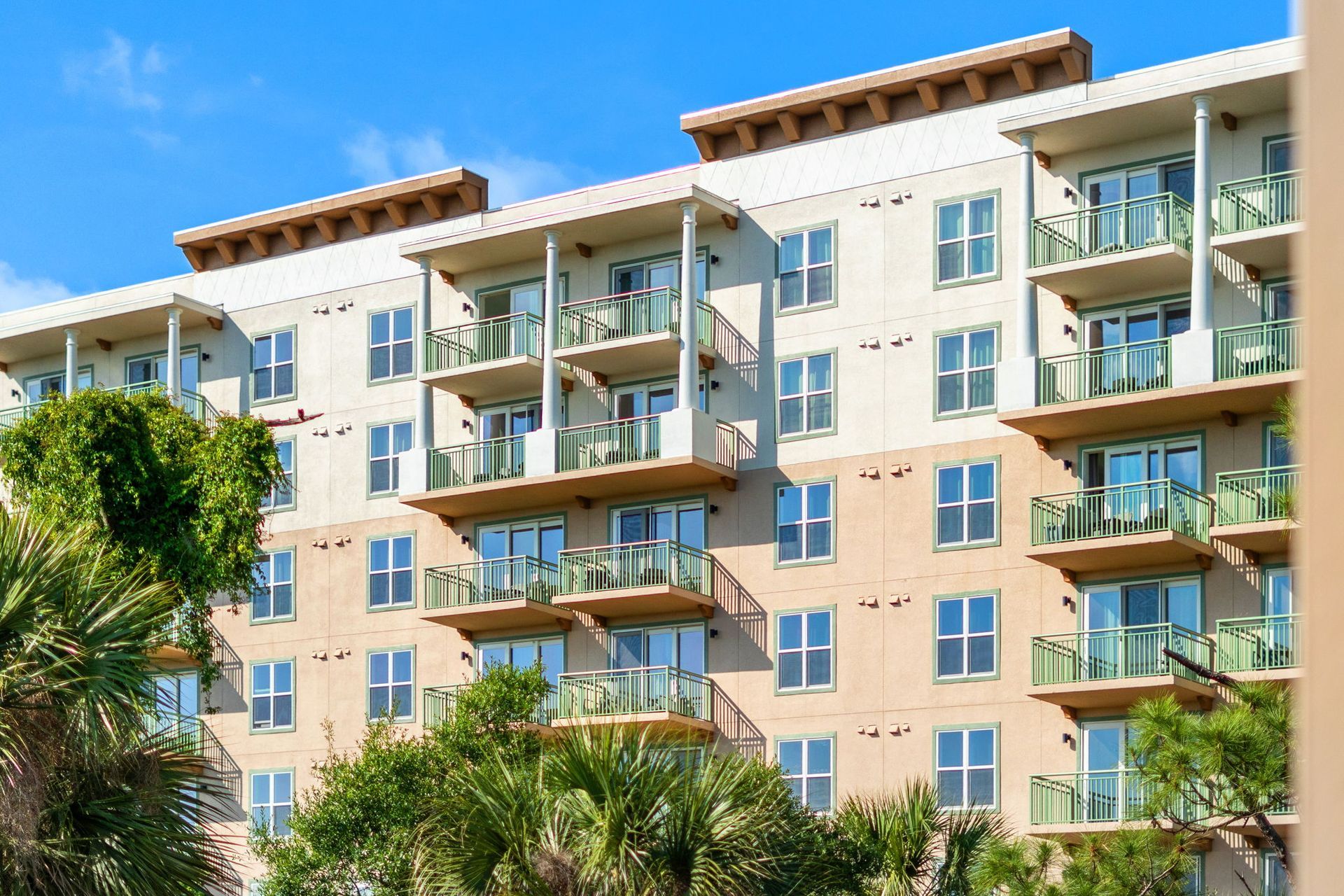 Modern beige condominium building in Merritt Island Florida next to the Merritt Island Airport with balconies and palm trees in front
