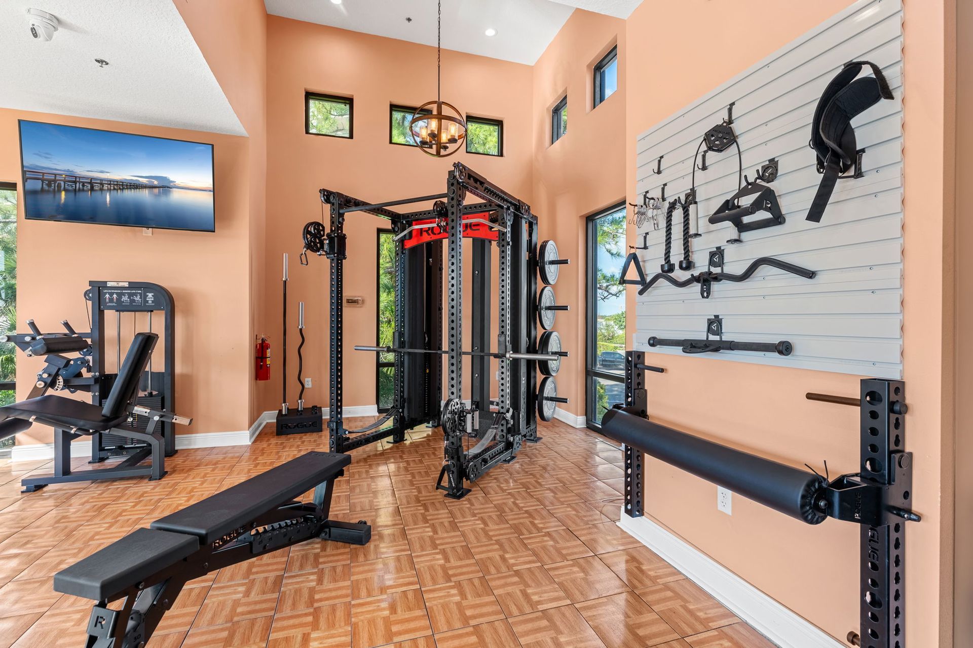 Home gym with cable machine, bench, and weight equipment on wooden floor