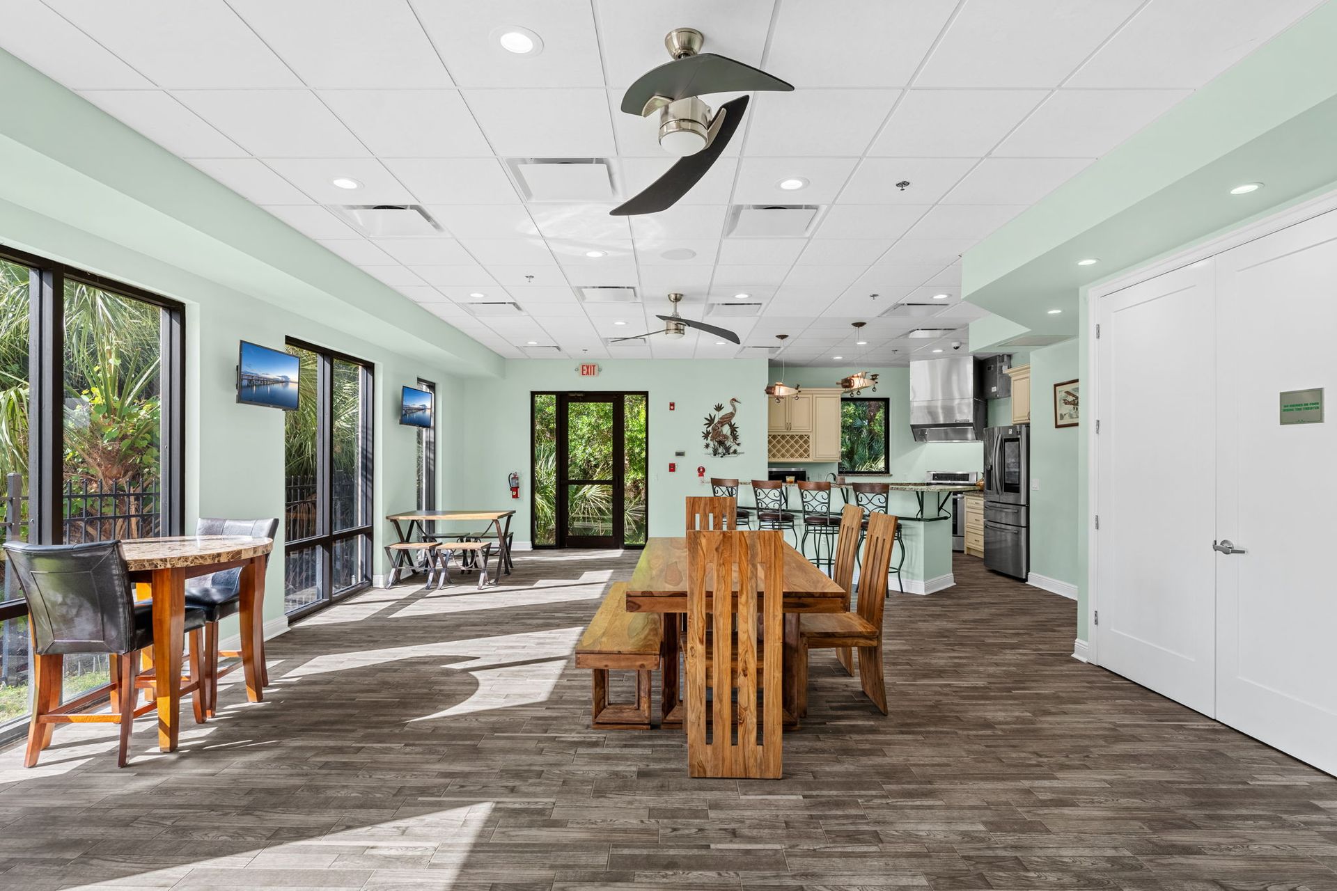 Bright modern open-plan room with tables, large windows, white walls, and wood flooring