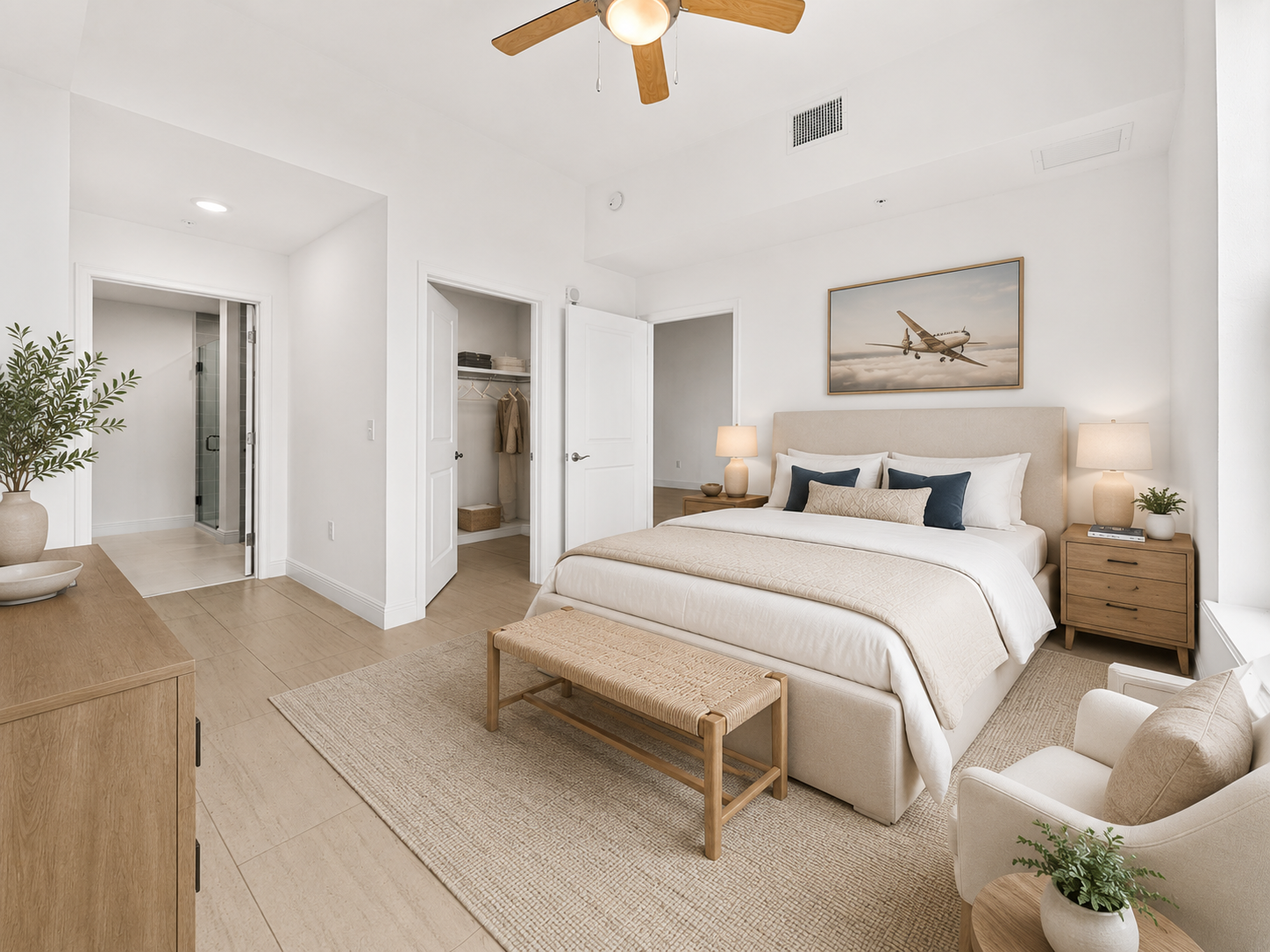 Bright, airy bedroom with a white bed, wicker bench, matching nightstands, and woven beige decor