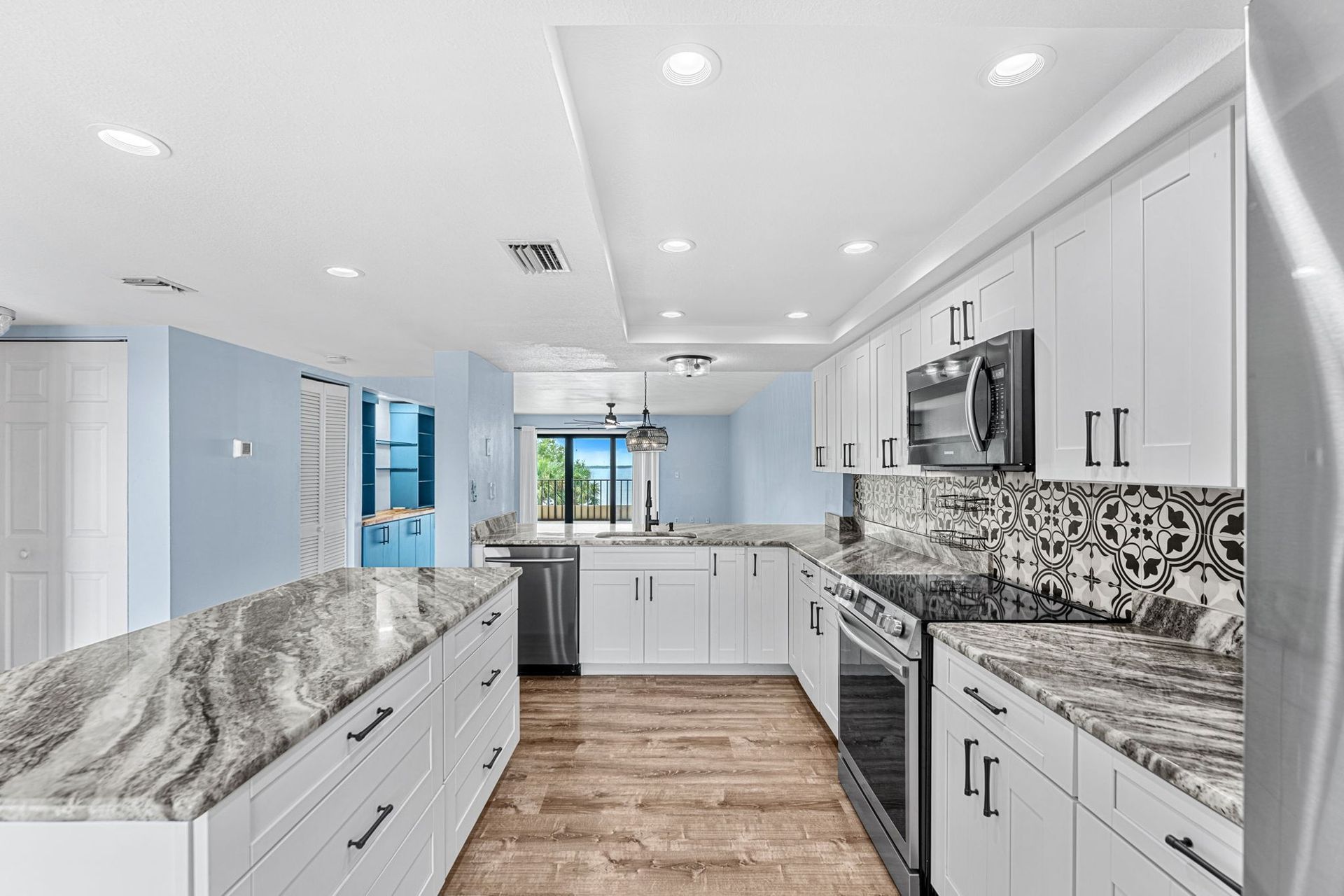 Bright updated Space Coast kitchen with white cabinets, stainless appliances and a granite island.