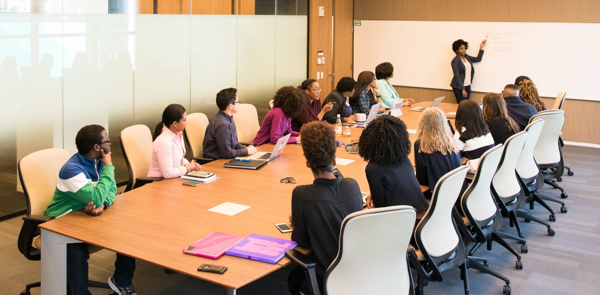 A group of people are sitting around a long table in a conference room.