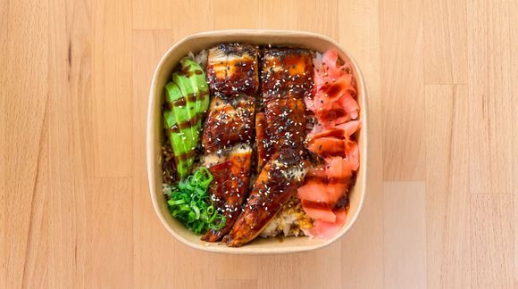 Overhead view of a bento box with glazed fish, rice, and colorful vegetables on a wooden table