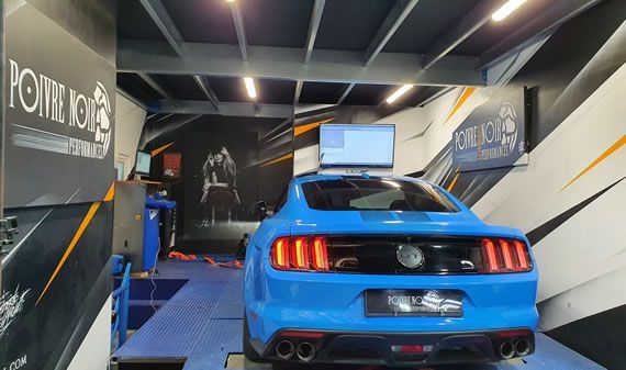 Ford Mustang bleue sur un dynamomètre dans un garage, en cours de test.